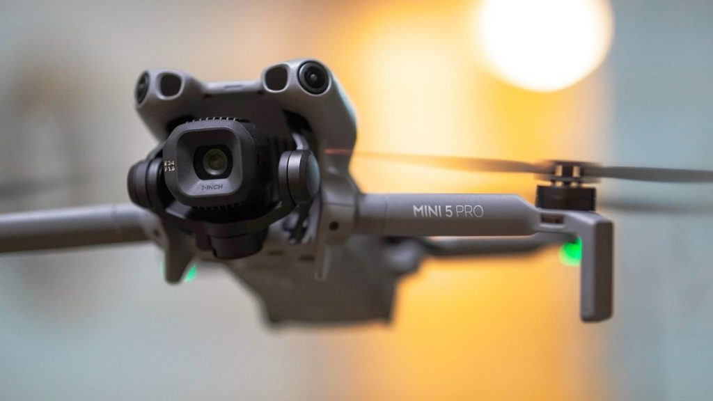 Detailed shot of a Mini 5 Pro drone in flight, highlighting its camera and propellers.